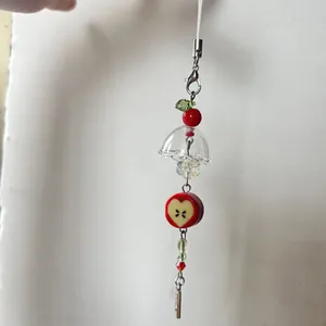 Handmade beaded phone charm featuring red apple and green leaf beads on a white cord