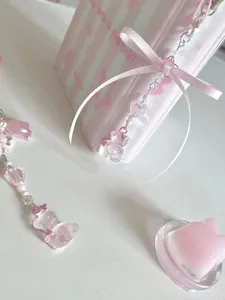 Détail d'un pendentif ours rose et perles de cœur avec nœud en ruban sur une lanière