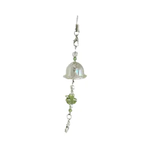 Handmade clover bell phone charm with iridescent glass and green beads on white background