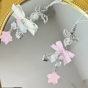 Handmade beaded phone charms with pink stars, strawberry pendants and silk bows on a mirror