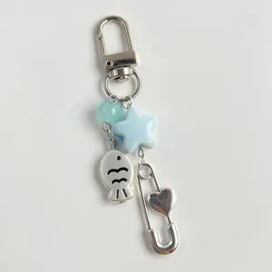 Charm perle poisson mignon avec étoiles bleues et épingle cœur argent sur fond gris