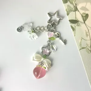 Détail d'une dragonne de perles avec pêche en résine rose et nœud en soie blanc