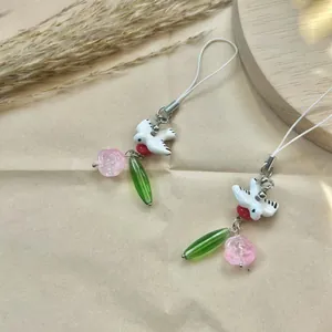 Handmade spring bird bag charm with pink rose and green leaf beads on paper background