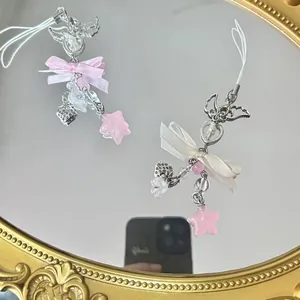 Detail of pink bow and star beaded phone charms on a vintage mirror decorative surface