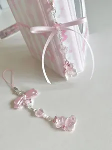 Détail du bijou de sac rose avec perles, nœud papillon et pendentif ours transparent