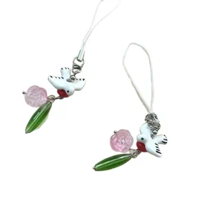 Minimalist flower and bird charms with pink blossoms and green leaf beads on a white loop