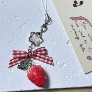 Pastel strawberry phone charm with red checkered bow and heart metal tag pendant