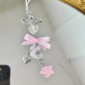 Close-up of pink satin bow, angel wing, pearl heart, and star charm for phone or bag