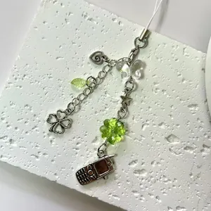 Lucky four-leaf clover beaded phone strap with green charms on a stone tray
