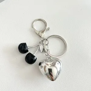 Portachiavi a cuore in argento lucido con ciliegie nere e moschettone su sfondo bianco