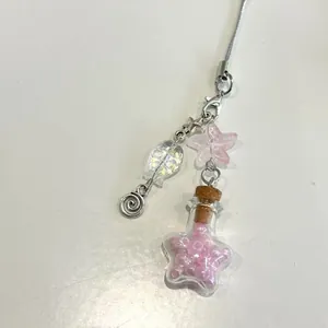 Vista macro de colgante de móvil botella con estrella de mar rosa y cuentas
