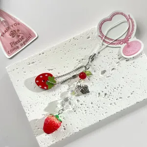 Cute red strawberry phone charm accessory with beads and silver chain on stone