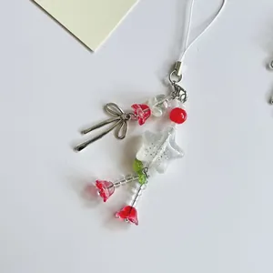 Detail van kralen telefoonhanger met zilveren strik en transparante sterren