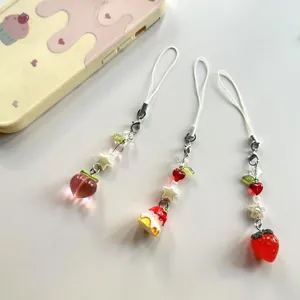 Détail de breloques en perles faites main avec des pendentifs fraise pêche et gâteau
