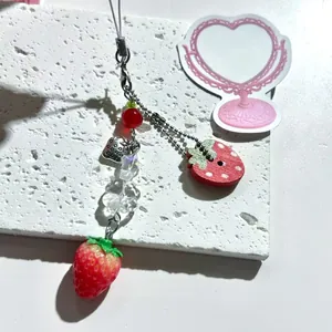 Sweet strawberry phone charm with realistic red pendant and heart metal tag on white stone