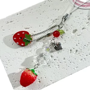 Sweet strawberry charm phone strap with red beads and silver chain on a white stone