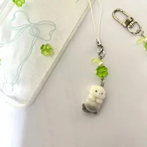 Cute plush sea otter phone charm with green clover beads and a matching white case