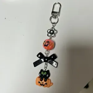Halloween phone charm featuring a black cat in a pumpkin with orange and black beads