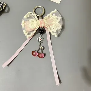Porte-clés nœud doux avec pendentifs cerises roses et détails en dentelle