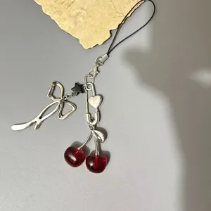 Y2K cherry bow phone strap with silver star and heart pendant on gray background