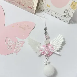 Close-up of pink lace angel wing charm with a white ribbon bow and soft plush pompom