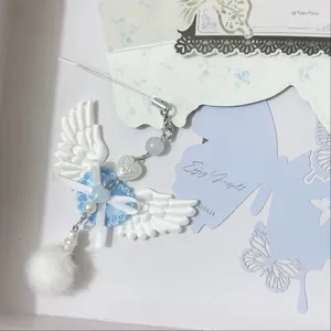 Porte-clés ailes d'ange Y2K avec broderie blanche, perles bleues et pompon doux en peluche