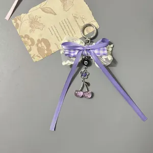 Porte-clés nœud en dentelle violette avec breloques cerise et fermoir en métal argenté