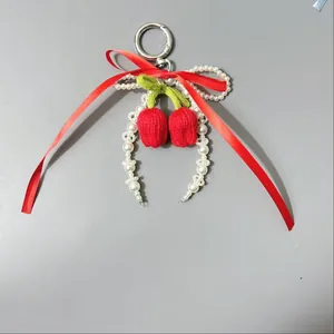 Detalle de colgante de cereza tejido a mano con lazo rojo y cuentas de perlas falsas