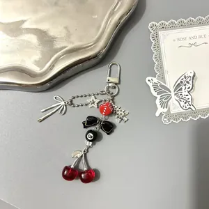 Porte-clés perlé style punk avec breloques cerise, dés et nœud sur plateau