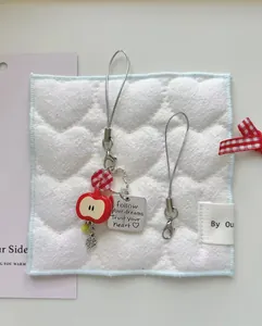 Detail of red apple resin pendant with engraved follow your dreams metal charm strap