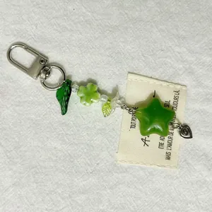 Macro detail of a green clover keychain with star beads and a metal heart charm