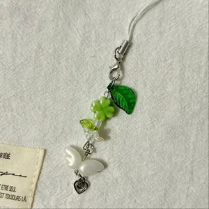 Detail of green clover phone strap with white butterfly beads and silver heart pendant