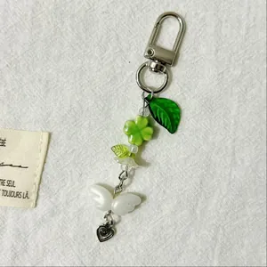 Fresh green four-leaf clover keychain with white flower beads and silver heart charm