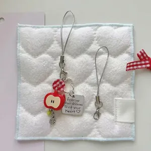 Handmade beaded phone strap with red apple charm and silver plate on quilted background