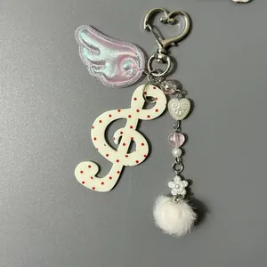 Porte-clés musical clé de sol à pois avec aile irisante et pompon blanc en peluche