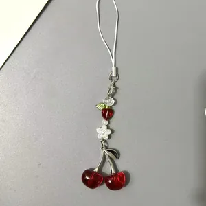 Cute cherry beaded phone charm with red resin fruit, small white flower and metal clasp