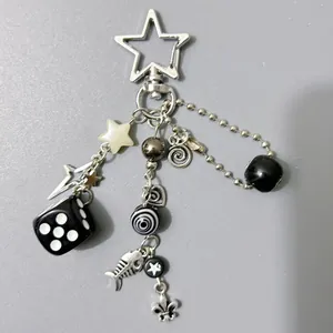 Gothic style keychain with silver heart, star, dice, and fishbone charms on grey background