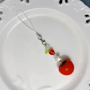 Schattige rode tomaat kralenhanger met hart- en steraccenten op een wit sierbord