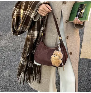 Detail of coffee brown suede hobo bag featuring a plush dog charm and pearl chain accent