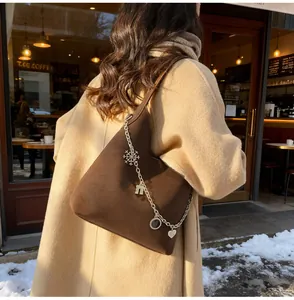 Close-up of dark brown suede tote bag with decorative silver charms and chain detail