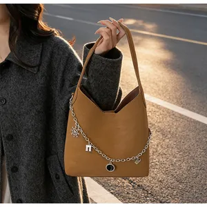 Detail of caramel tote bag featuring stylish silver charms with heart and snowflake motifs