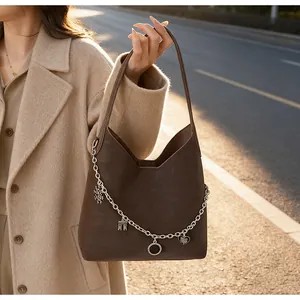 Detail of dark brown matte leather tote bag featuring silver chain charms and pendants