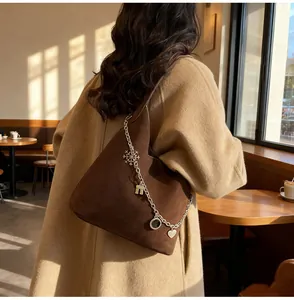 Detail of dark brown suede tote bag with silver chain and decorative metal charms