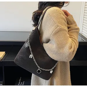 Detail of dark brown suede tote with decorative silver chain and metallic charms