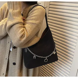 Close-up of black suede tote bag featuring silver chain with heart and tower charms