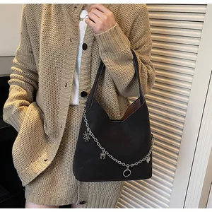 Detail of black tote bag featuring matte texture and silver chain with fashion charms