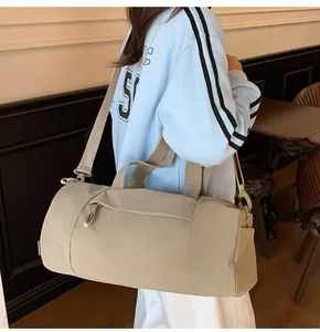 Side view of beige cylindrical duffel bag worn as a shoulder bag in a cafe setting