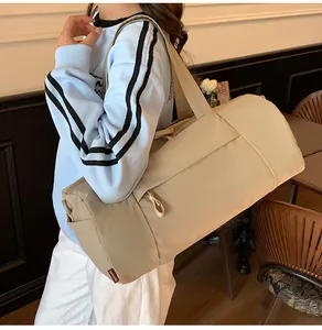 Detail view of khaki nylon duffel bag with wide strap in a cozy indoor setting