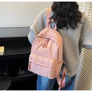 Détail du sac à dos rose en nylon matelassé avec fermetures tressées et sangle tendance