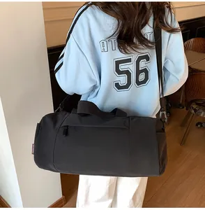 Detail of black cylindrical sports bag with adjustable strap and side zipper pocket